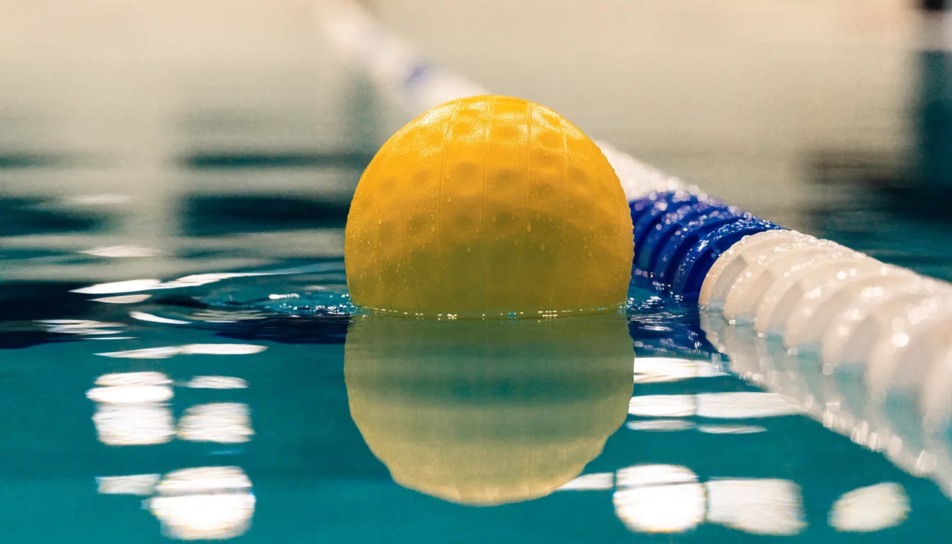 Ein gelber Wasserball treibt in Nahaufnahme auf der Wasseroberfläche neben einer Leine mit Bojen.