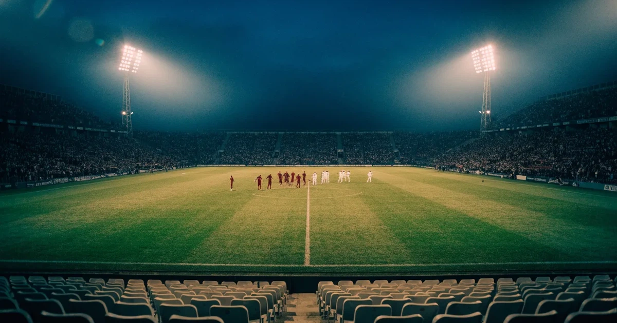 Ein Fußballstadion am Abend unter Flutlicht aus der Ferne gesehen, die Tribünen sind leicht beleuchtet und der Himmel dunkelblau.